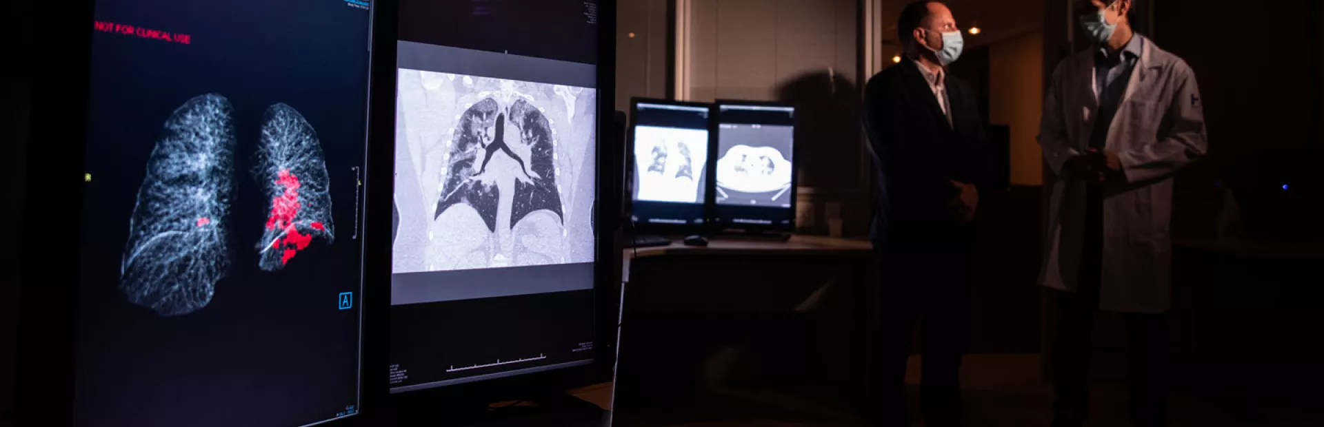 Image of scientists, wearing masks, discussing lung scans