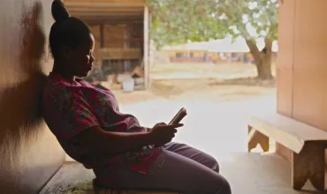 Telemedicine woman in Ghana on a bench looking at her mobile phone