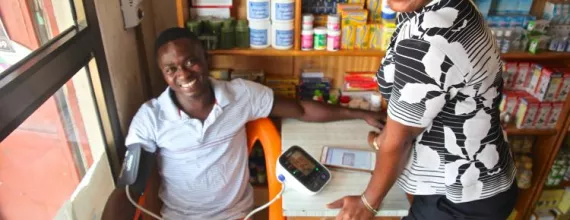 Image of patient in Ghana getting his blood pressure measured by a woman