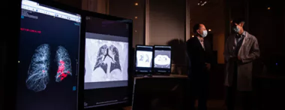 Image of scientists, wearing masks, discussing lung scans