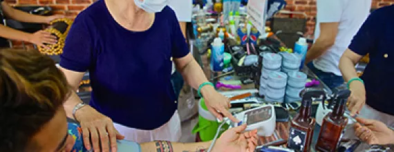 Woman wearing a mask measures blood pressure of a young man at a hair salon in Vietnam