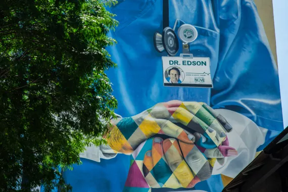 A grafitti on a house wall in Sao Paulo, Brazil showing an illustration of a health worker holding the hand of a patient