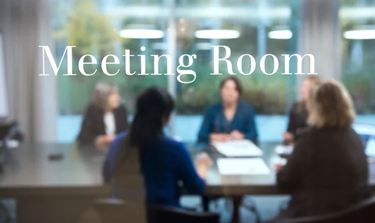 Transparent meeting room door with blurry business people in the background