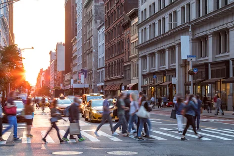 Crowded city with people crossing the street at sunset