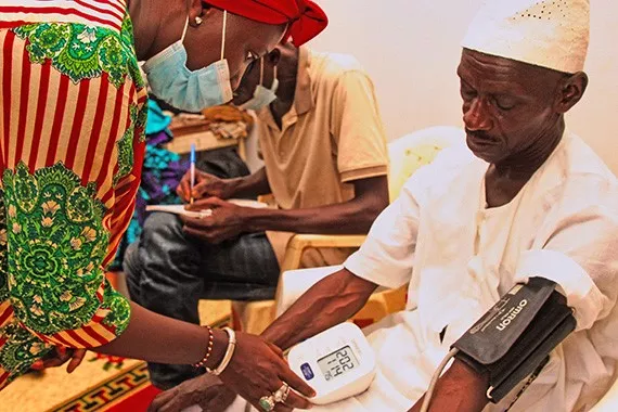 An African nurse performs a blood pressure check on an elderly African patient